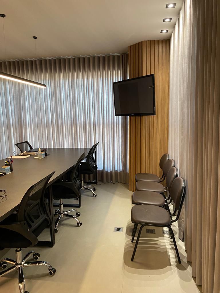 Escritório moderno da BBI Serviços, com computadores e mesa de reunião.